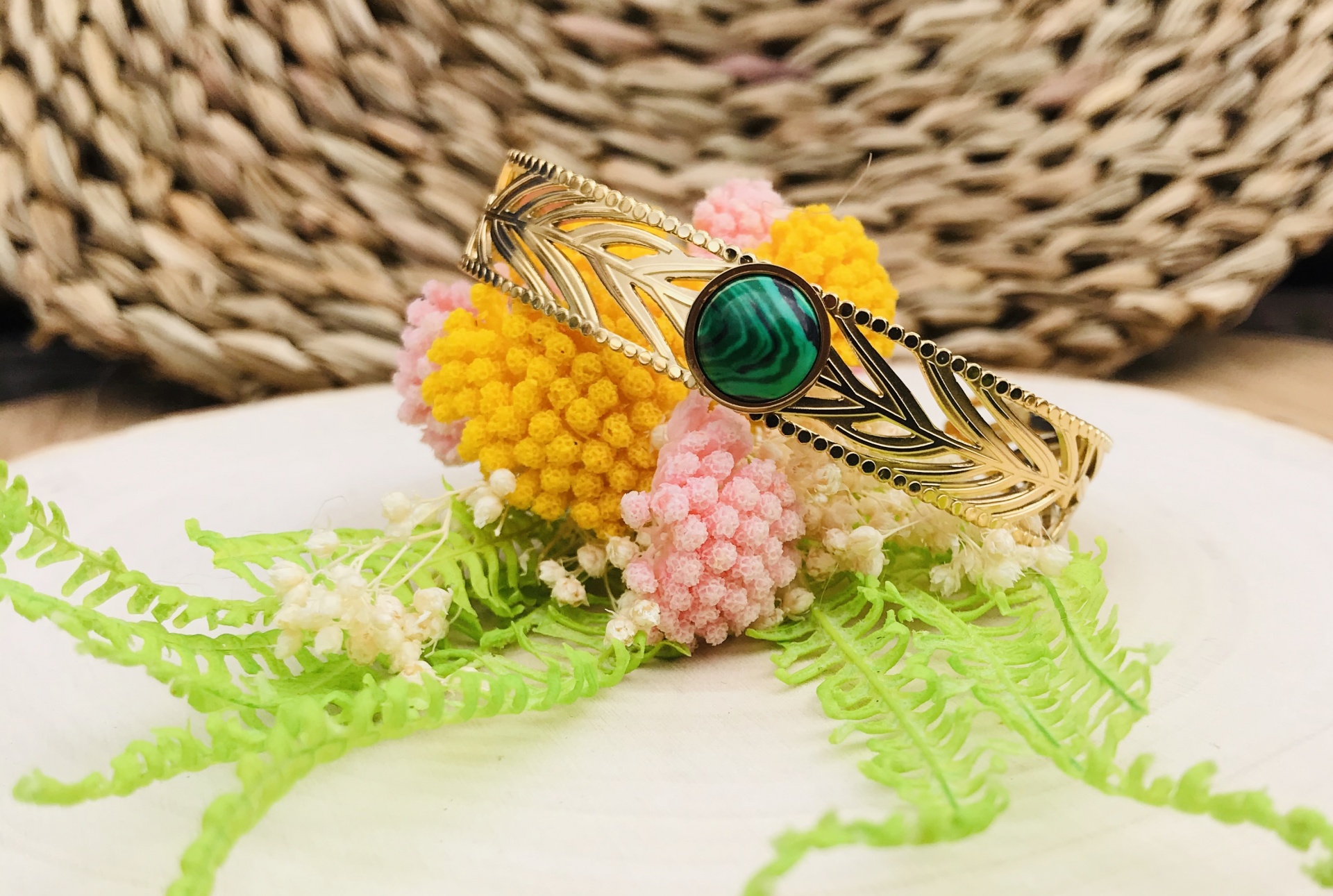 Pulseira dourada com pedra verde e flores artificiais coloridas