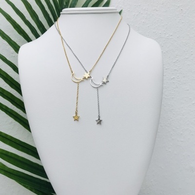 Colares dourado e prateado com pendentes de lua e estrela em suporte branco