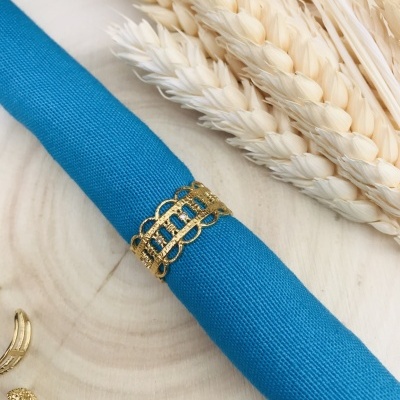 Guardanapo azul com argola dourada e trigo seco sobre madeira