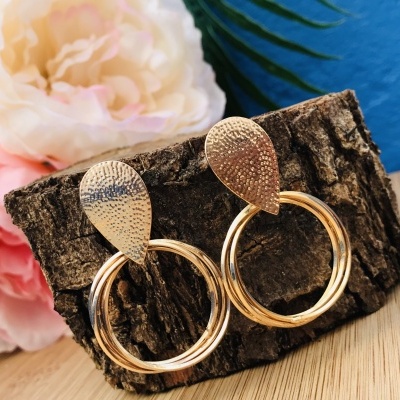 Brincos dourados círculo com textura martelada apoiados em casca de árvore