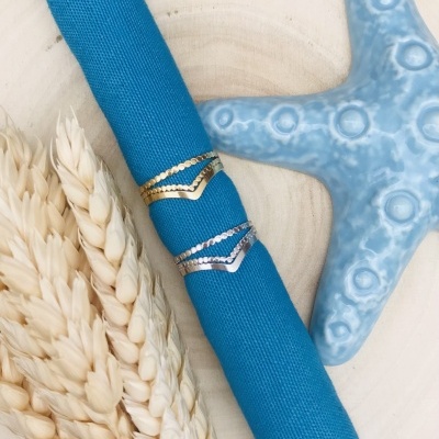 Anéis dourado e prateado sobre tecido azul com estrela-do-mar e espigas de trigo ao lado