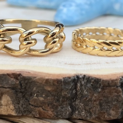 Quatro anéis dourados com diferentes designs sobre base de madeira rústica