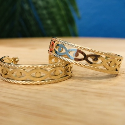 Brincos dourados com padrão de círculos sobre madeira clara