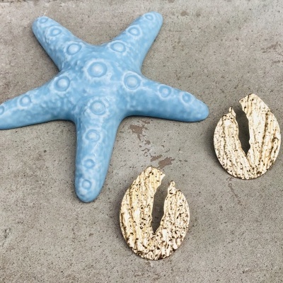 Estrela-do-mar azul em cerâmica e duas peças ovais bege texturizadas sobre superfície cinza