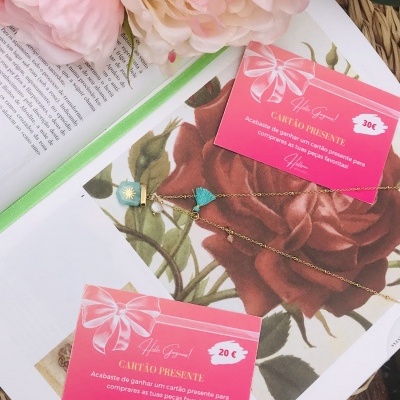 Cartões presente rosa com valores em euros sobre revista com ilustração de rosas e corrente dourada com pingentes