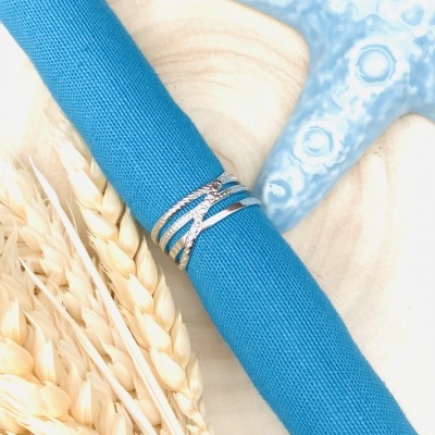 Anel prateado em tecido azul com espigas de trigo e estrela-do-mar azul ao fundo