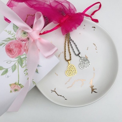 Colares em forma de coração dourado e prateado com padrão de corações, bola rosa de rede, prato branco e caixa decorativa com fita cor-de-rosa.