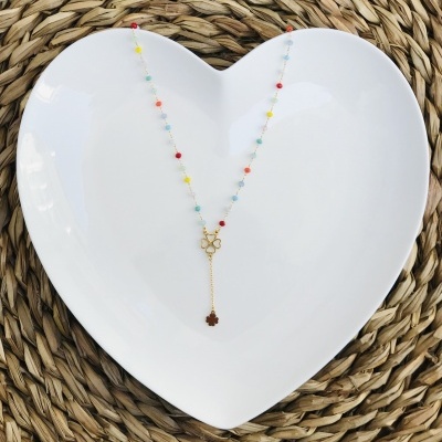 Colar com contas coloridas e pendente de flores sobre prato branco em forma de coração