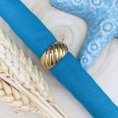 Pulseira azul em tecido com fecho dourado texturizado sobre madeira com estrela do mar azul e trigo