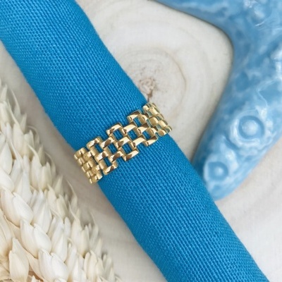 Anel dourado sobre tecido azul com fundo decorativo bege e azul