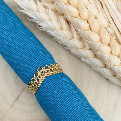 Guardanapo azul com argola dourada e espigas de trigo brancas sobre madeira