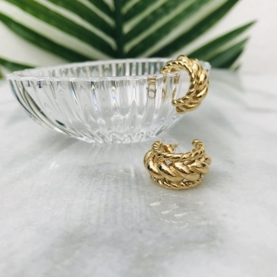 Brincos dourados trançados com taça de vidro e folha verde ao fundo