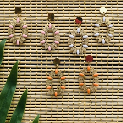 Brincos coloridos em bambu com folhas verdes ao lado