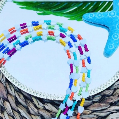 Colares coloridos em contas de plástico com formas variadas sobre espelho e estrela do mar azul