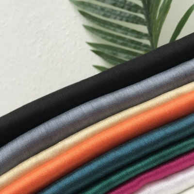 Tecidos coloridos dobrados com textura suave e uma folha verde ao fundo