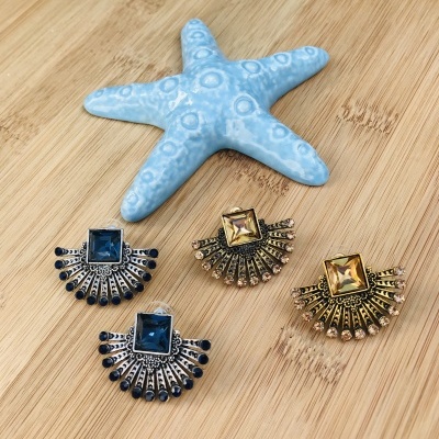 Quatro brincos com pedras coloridas e estrela do mar azul em madeira clara