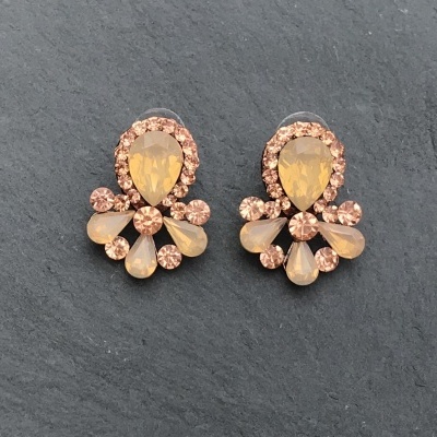 Brincos decorativos com pedras amarelas e castanhas em fundo escuro