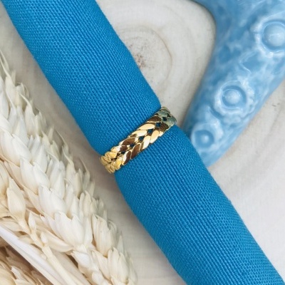 Anel dourado com padrão de escamas e guardanapo azul