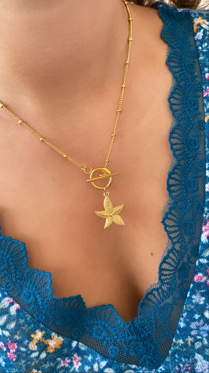 Colar dourado com pendente de estrela do mar e vestuário azul com renda