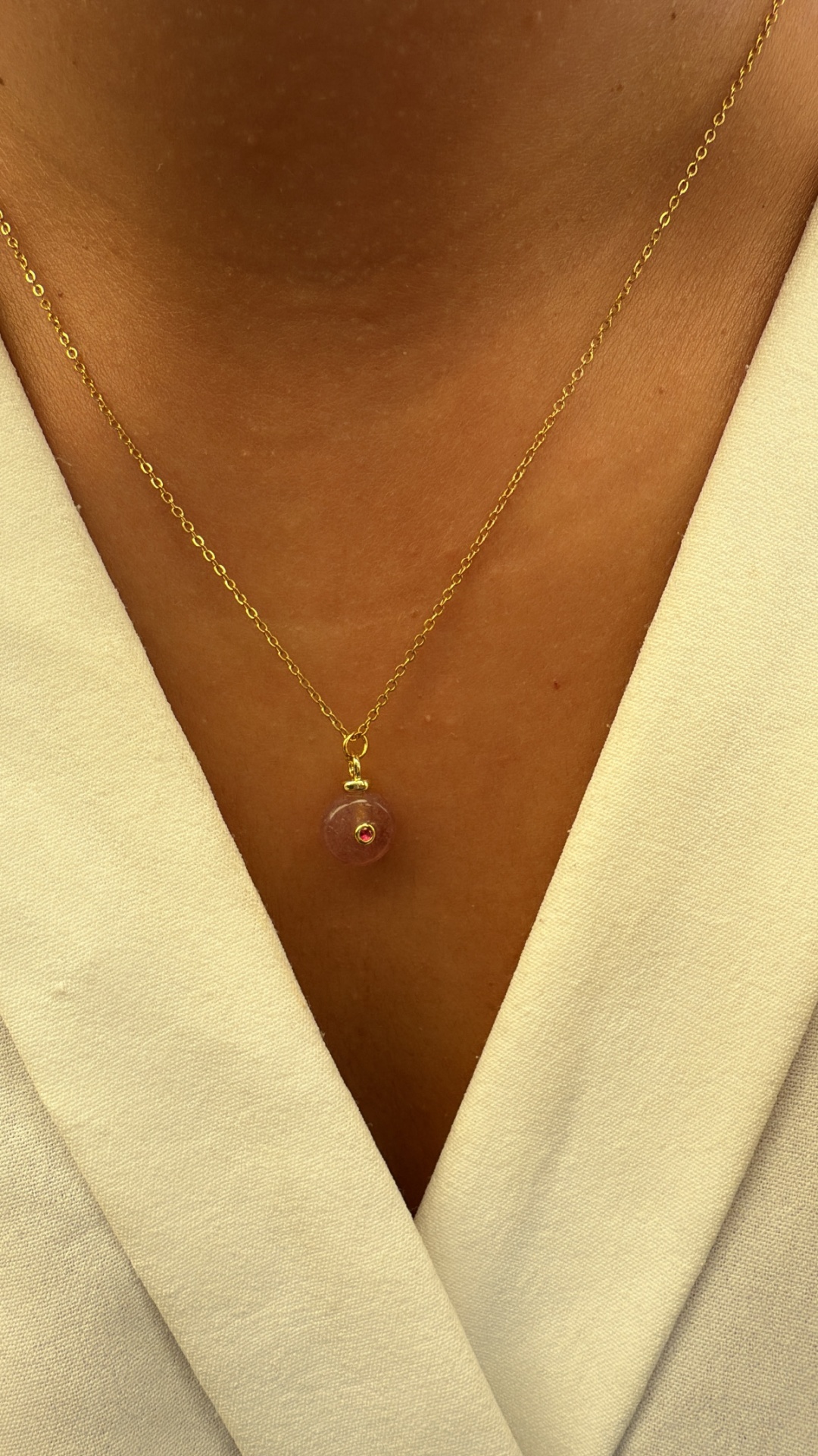 Colar dourado com pendente redondo rosa em pele castanha e vestido branco