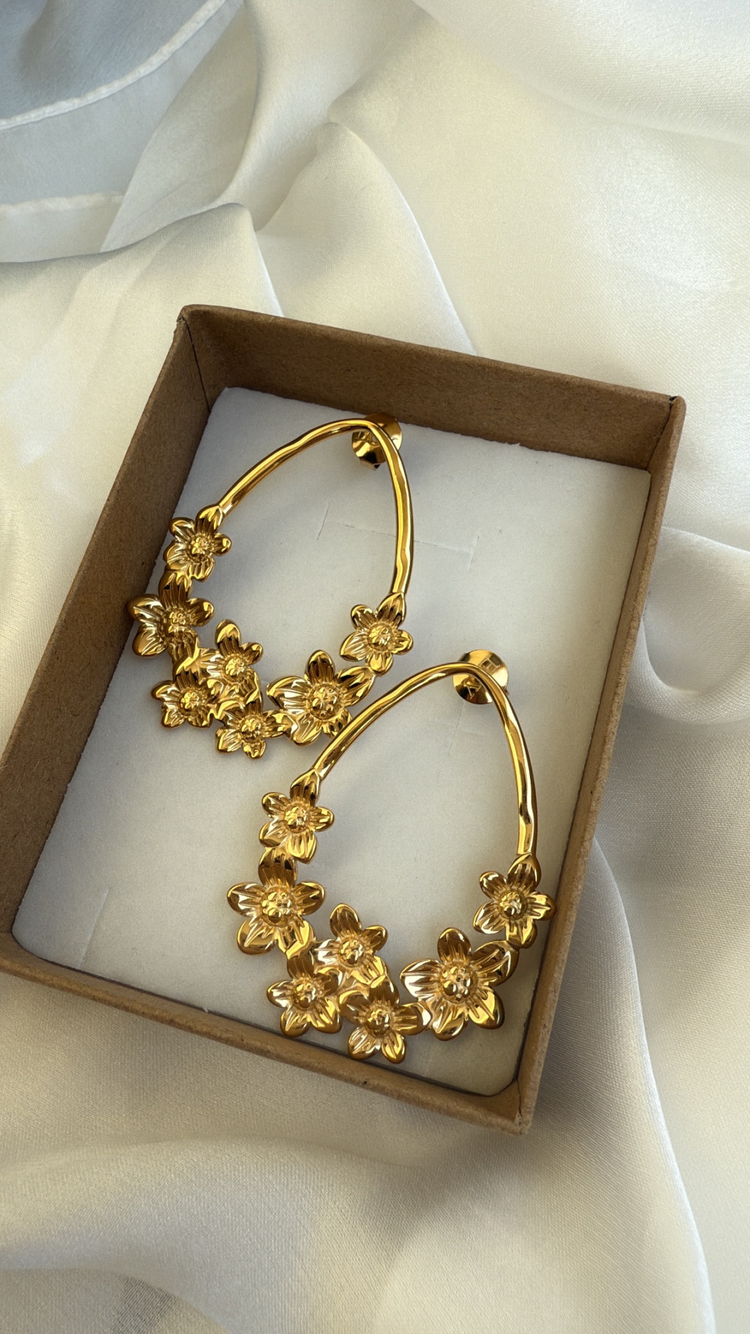Brincos dourados com flores em caixa de cartão