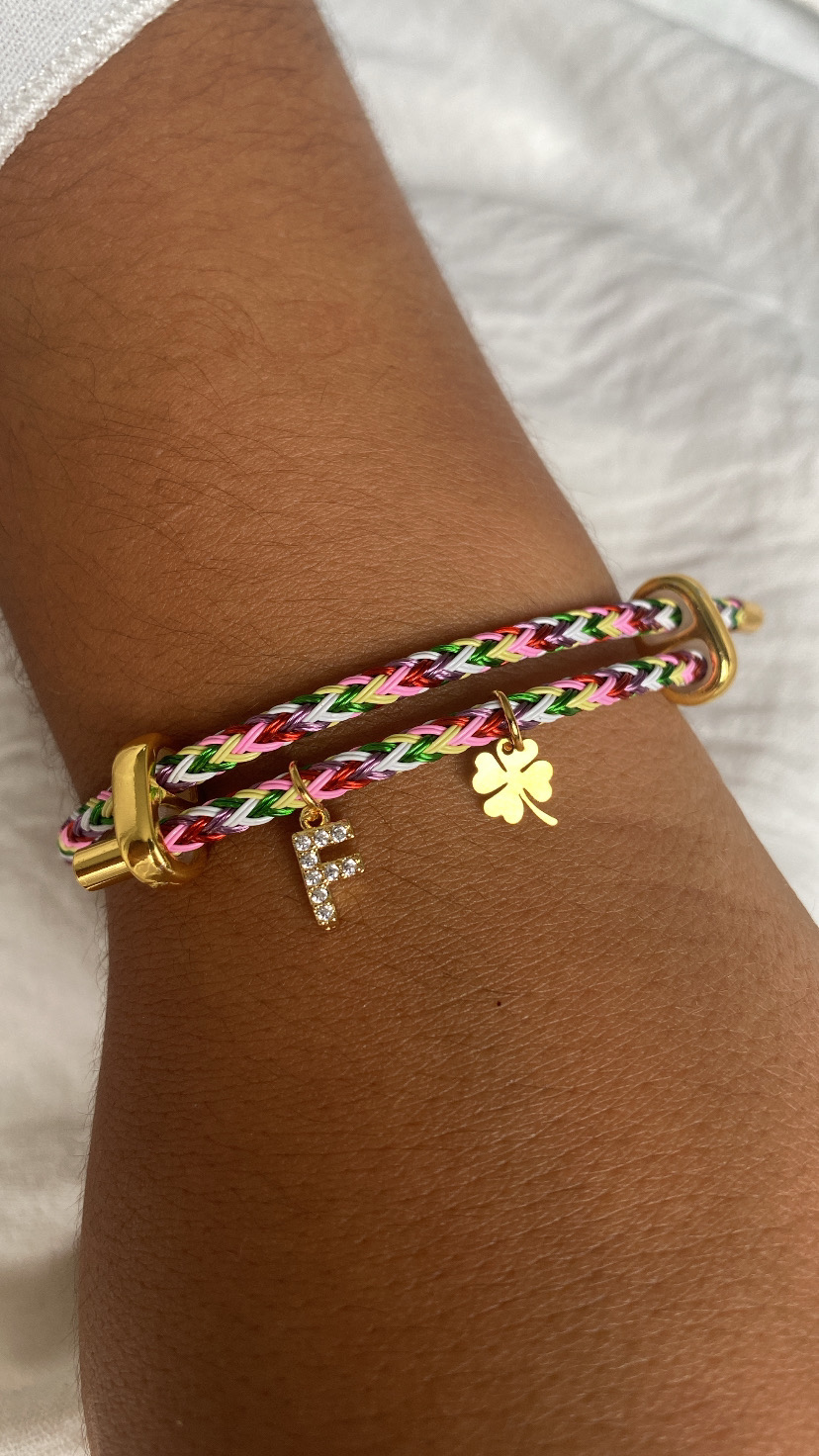 Pulseira trançada colorida com pendentes dourados em pulso castanho