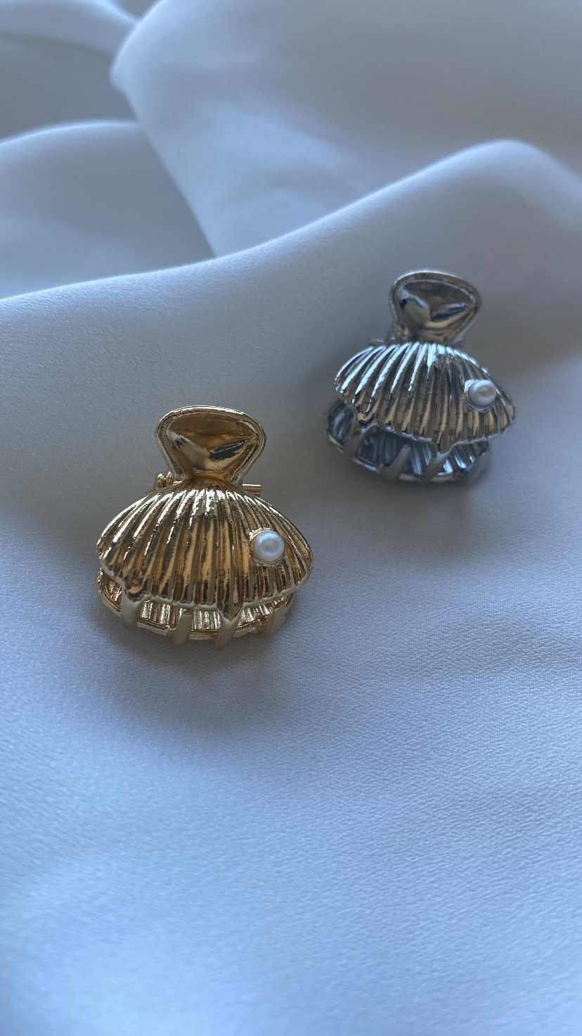 acessórios em forma de concha dourado e prateado com pérola sobre tecido branco