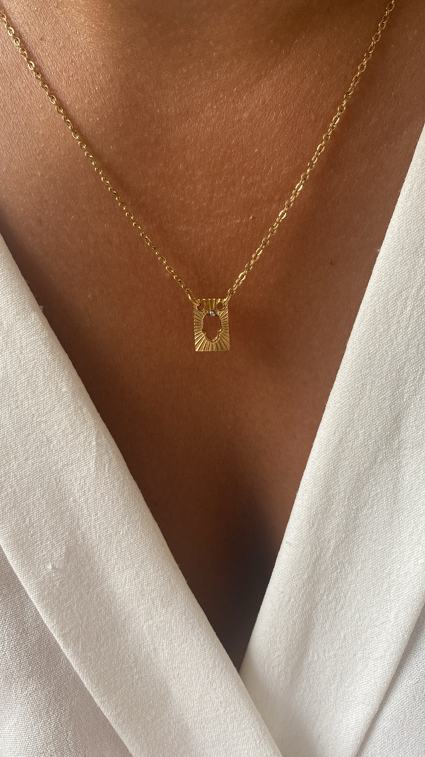 Colar dourado com pendente retangular em pele castanha e camisa branca