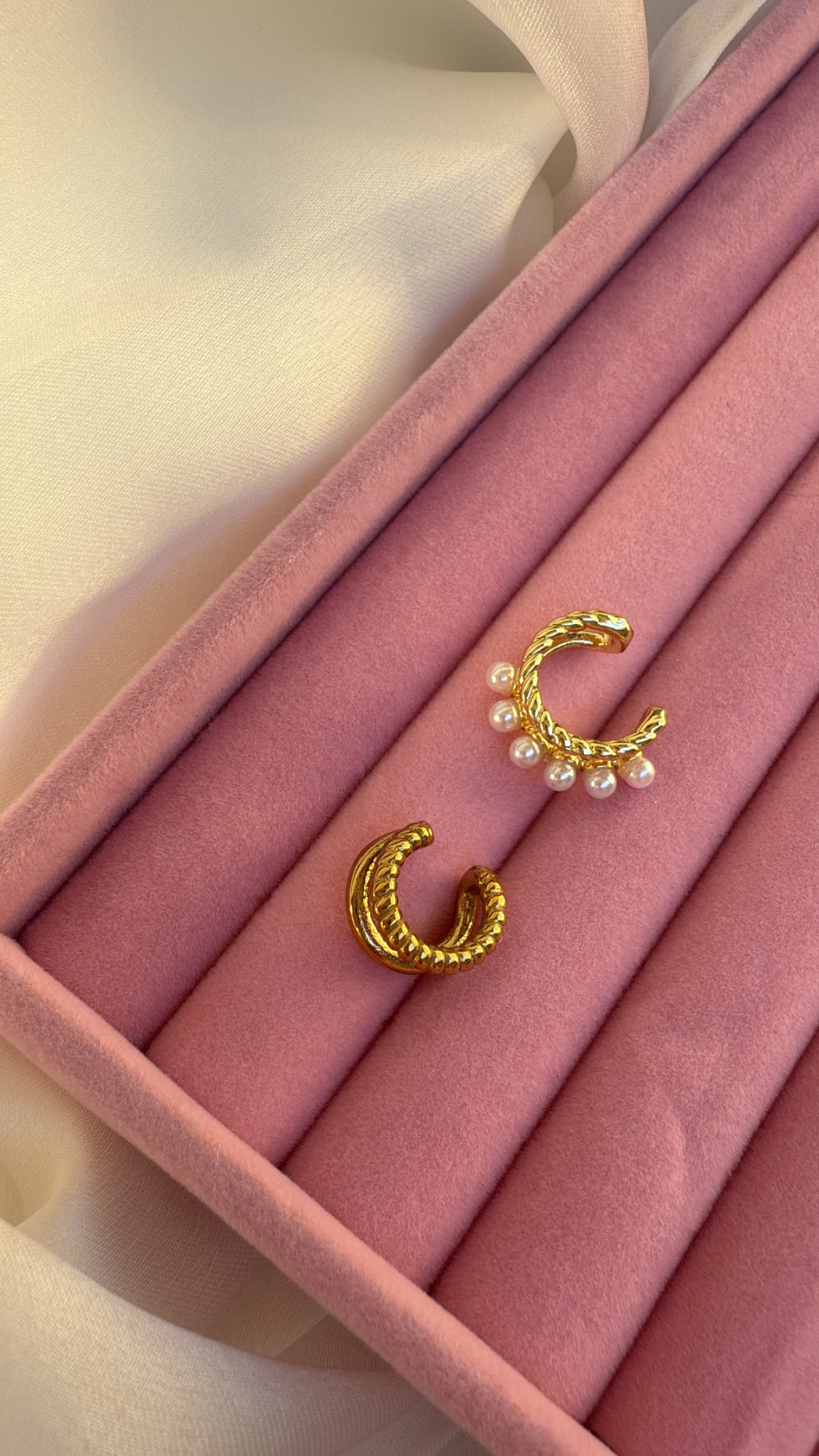 Brincos dourados em estojo rosa aveludado.