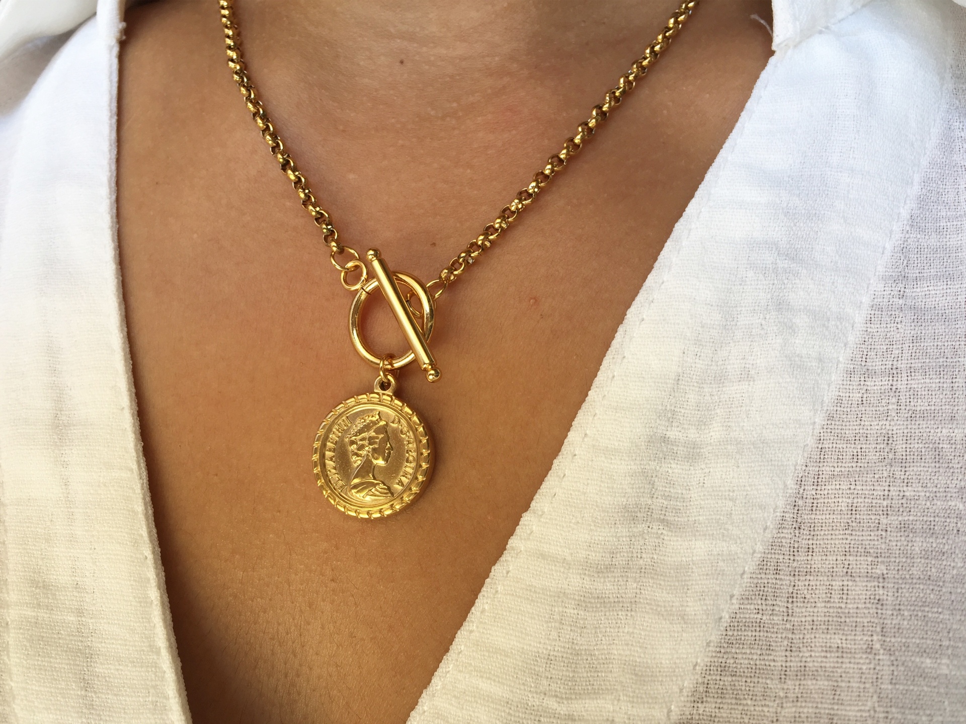Colar dourado com pendente redondo e camisa branca