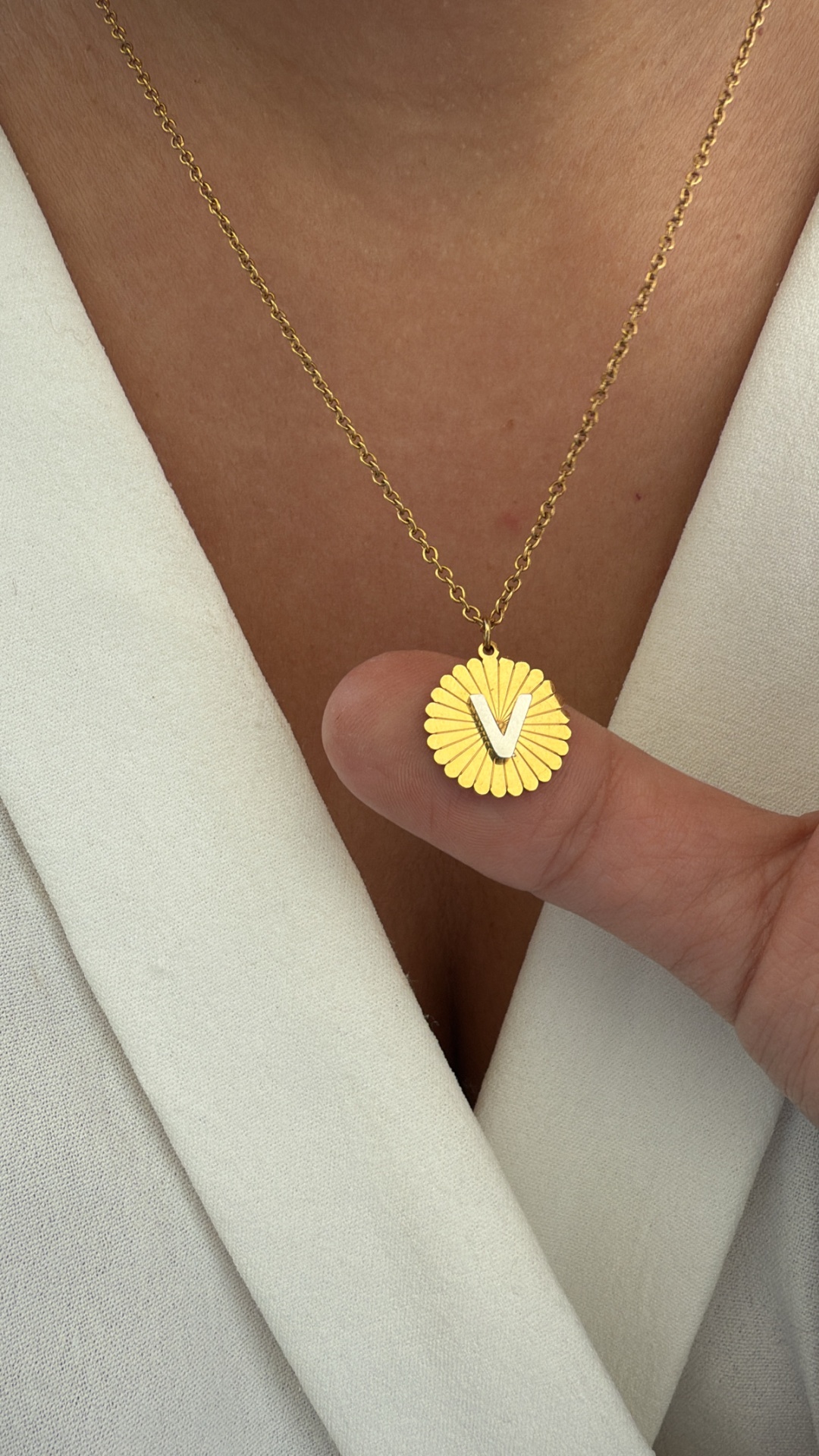 Colar dourado com pendente redondo e letra V em relevo