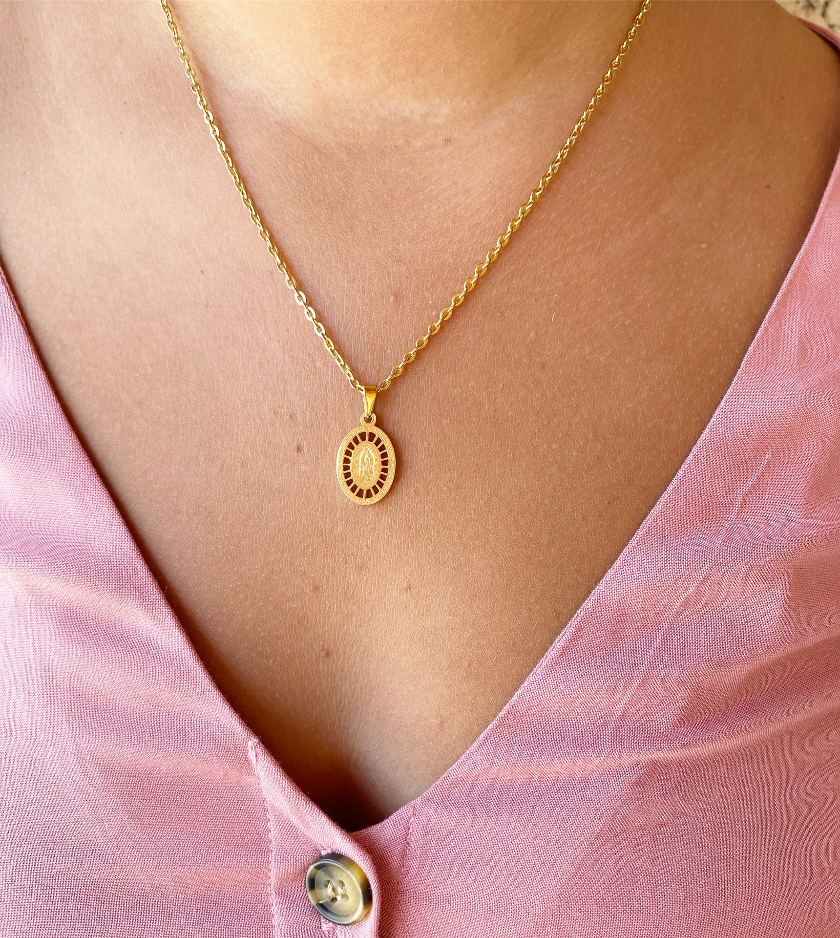 Colar dourado com pendente oval usado com blusa rosa