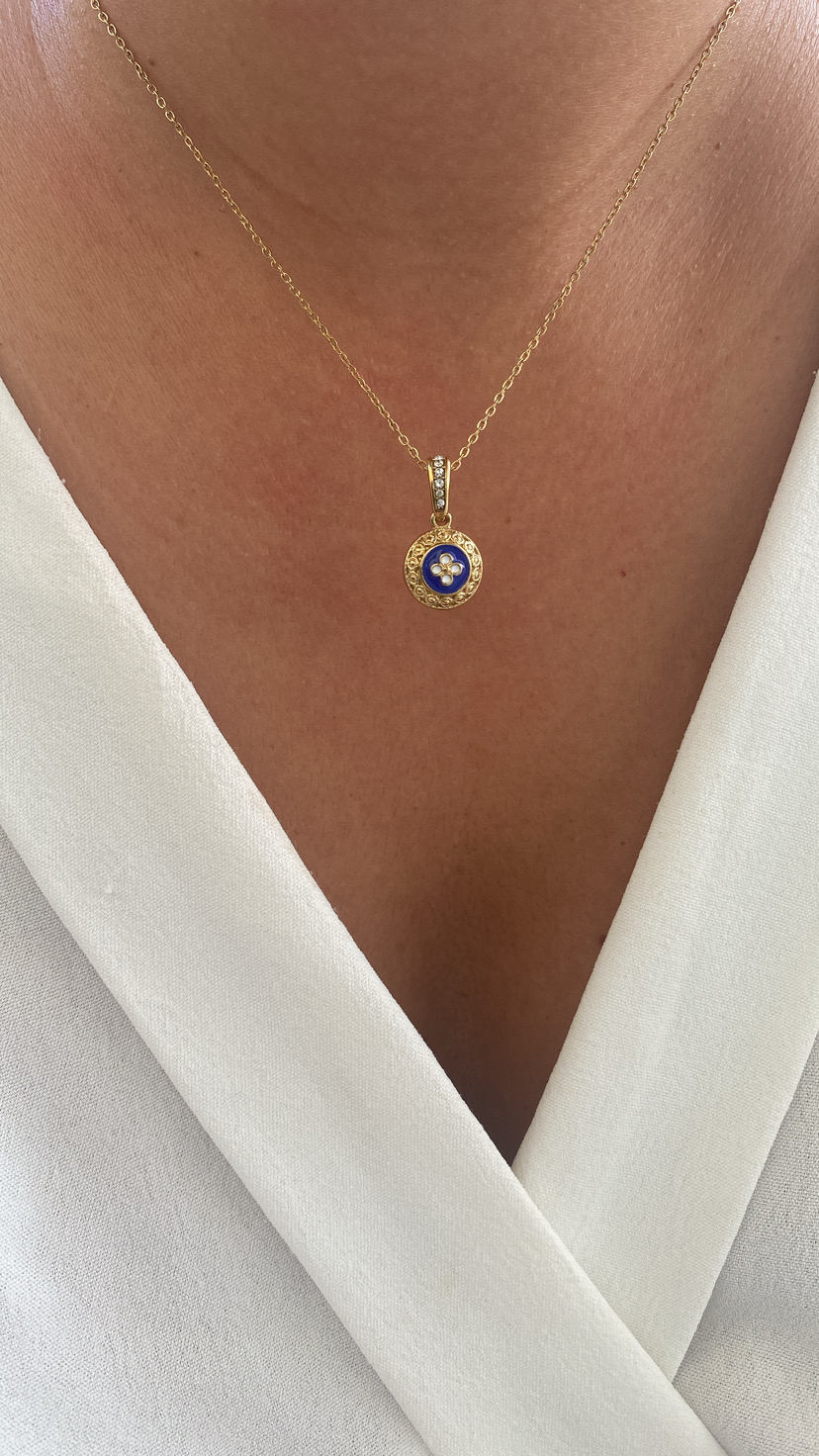 Colar dourado com pendente azul e flor branca