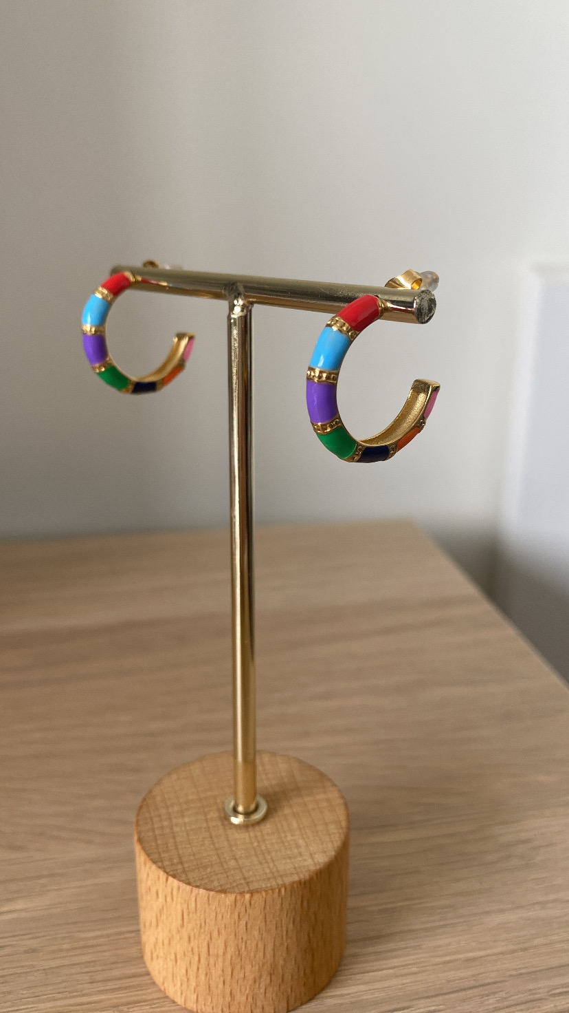 Par de brincos argola metálicos dourados com segmentos coloridos em suporte de madeira