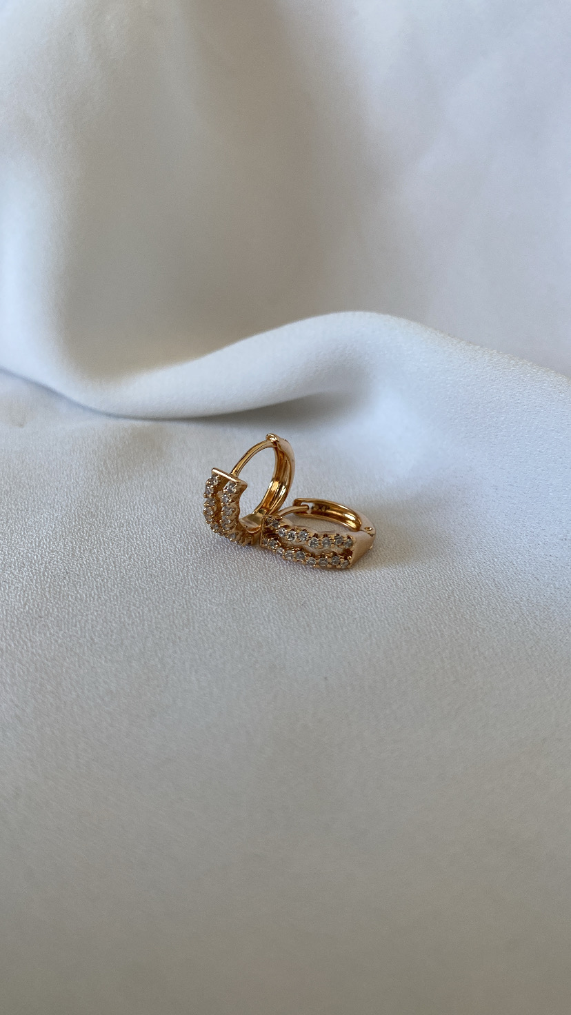 Brincos dourados com pedras sobre tecido branco