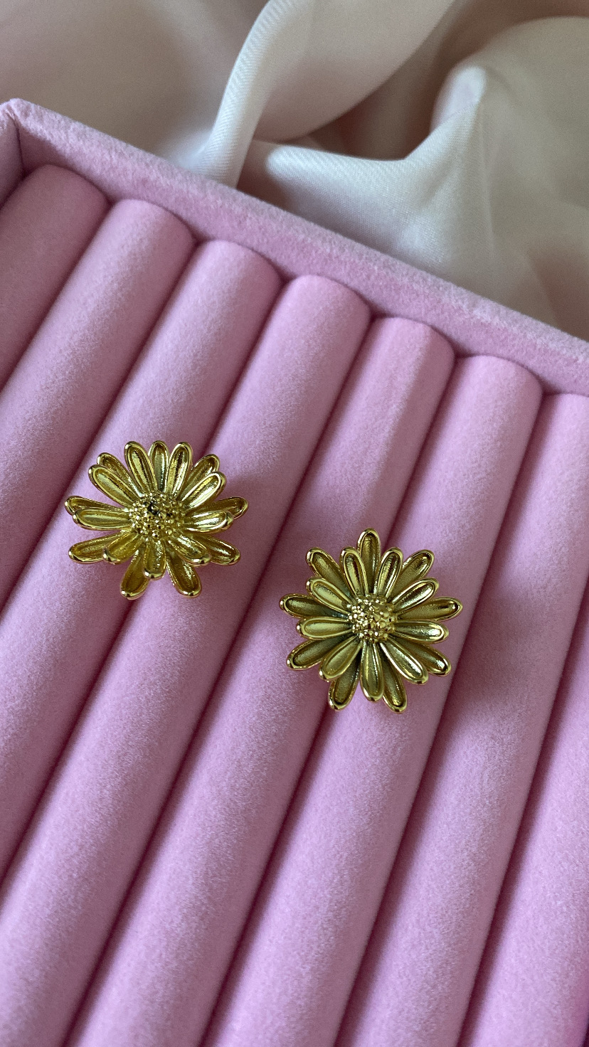 Brincos dourados em forma de flor numa caixa rosa de veludo