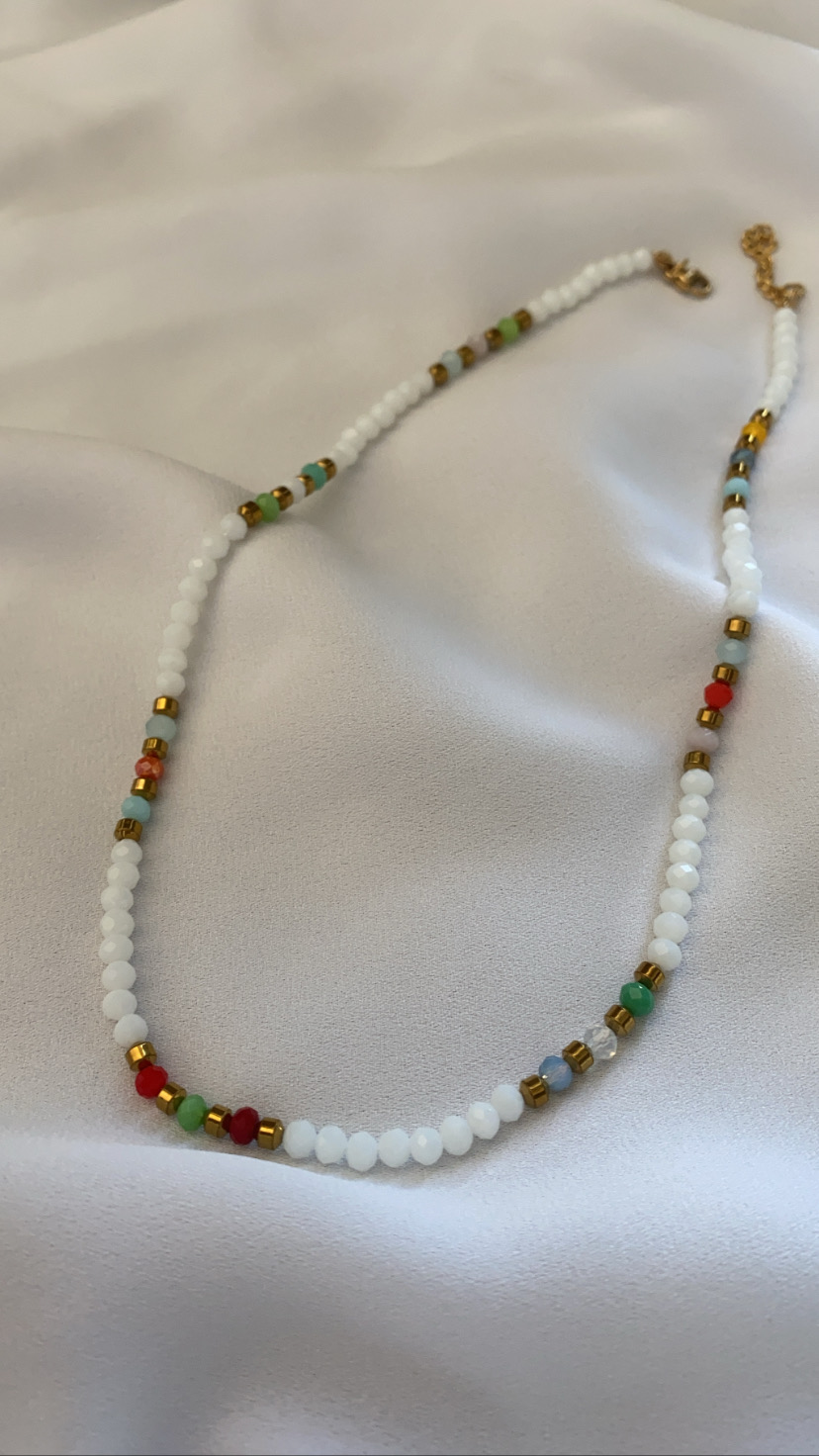Colar de contas brancas e coloridas sobre tecido branco