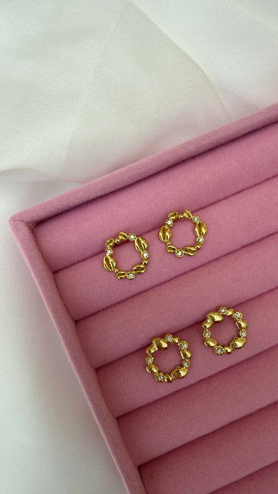 Brincos de argola dourados com pedras em caixa de veludo cor-de-rosa