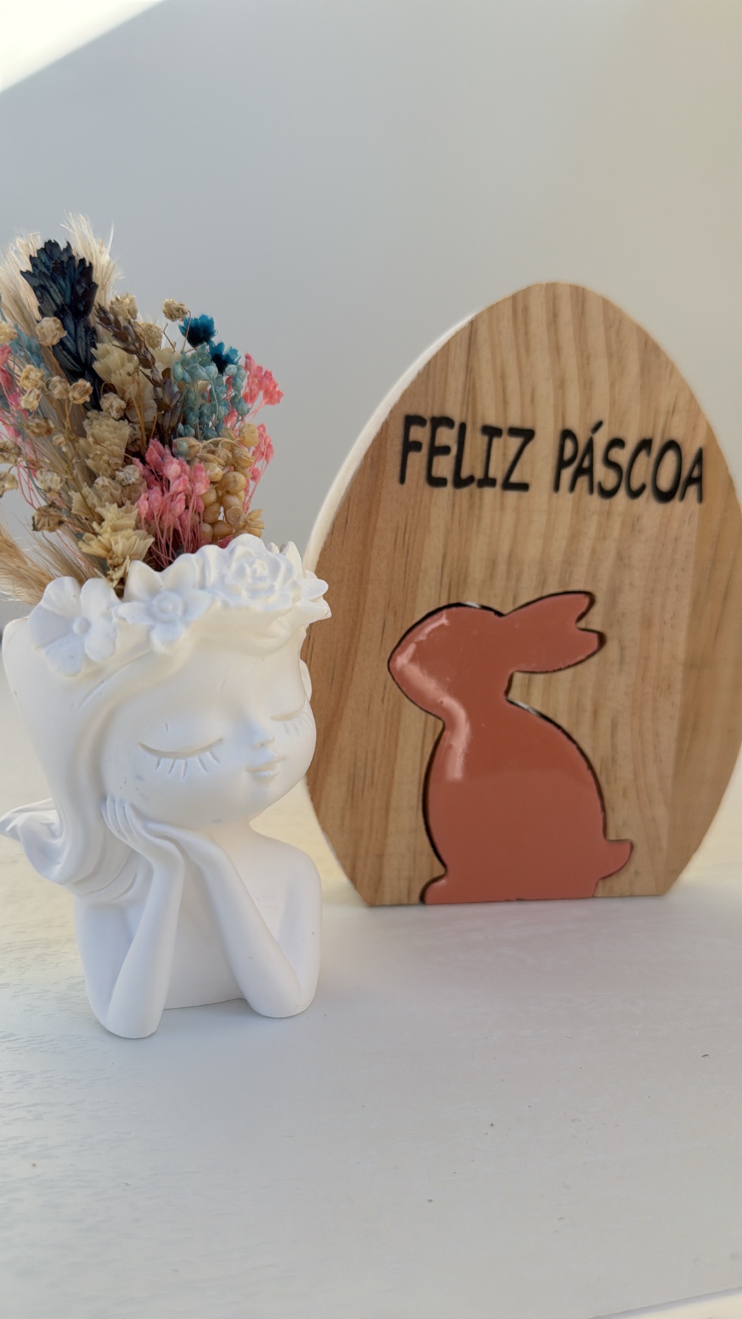 Vaso cerâmico com flores secas e placa de madeira decorativa de Páscoa.