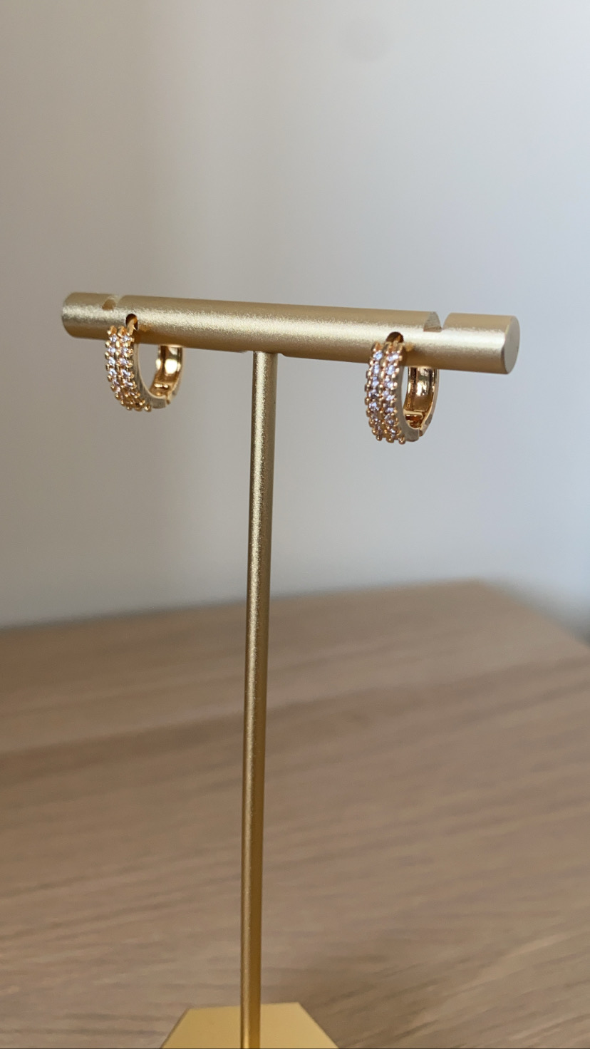 Brincos dourados com cristais num suporte dourado