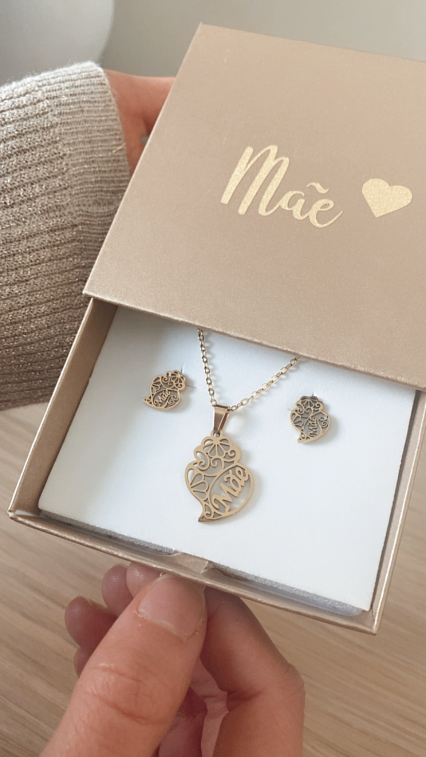 Conjunto de joalharia dourado com pendente e brincos, em caixa bege com palavra 