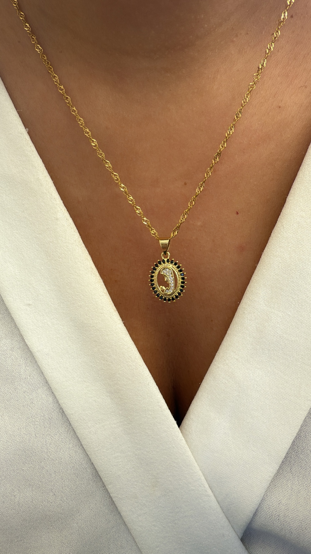 Colar dourado com pendente oval decorado e roupa branca
