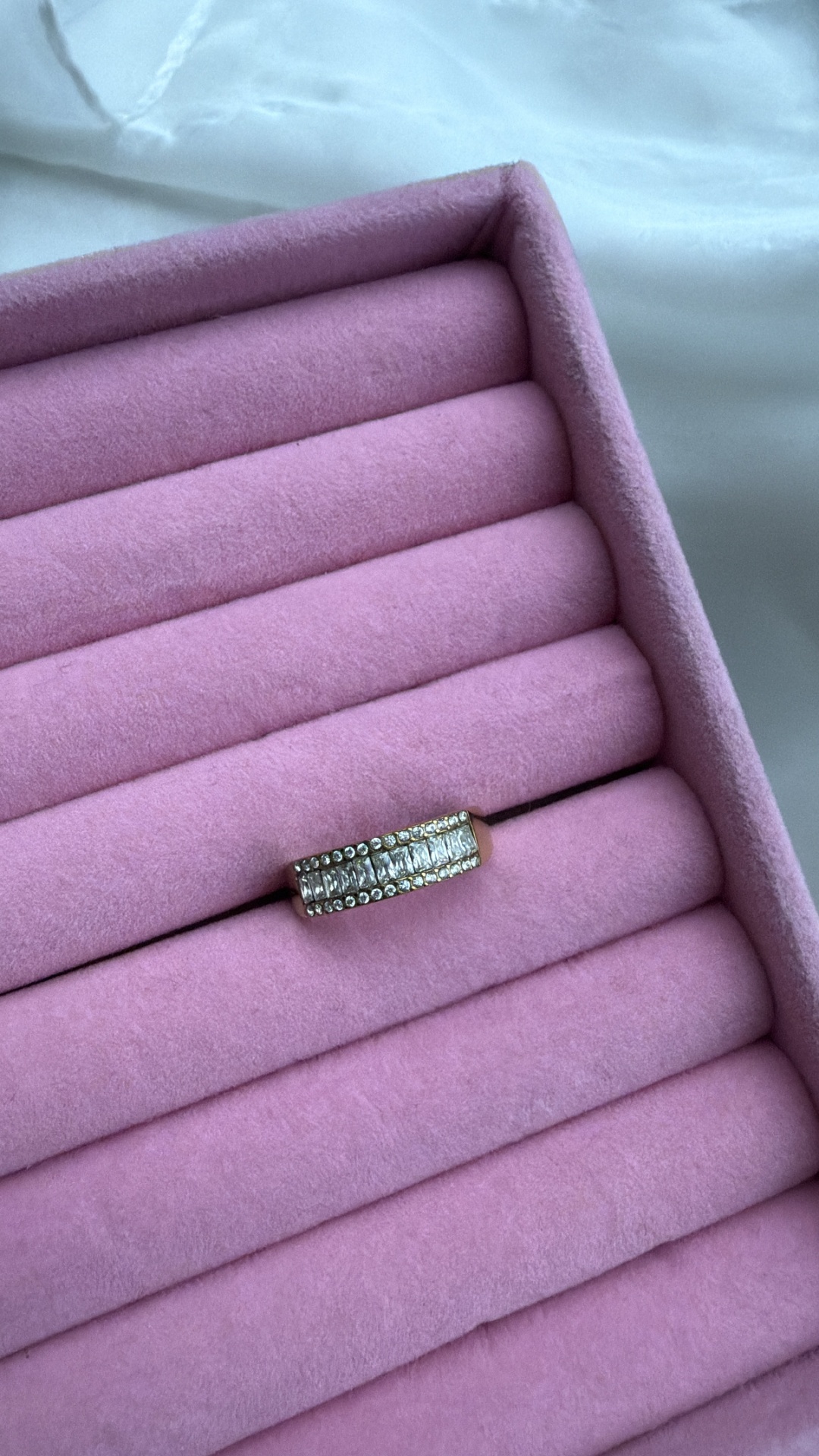 Anel dourado com pedras numa caixa rosa de veludo para joias
