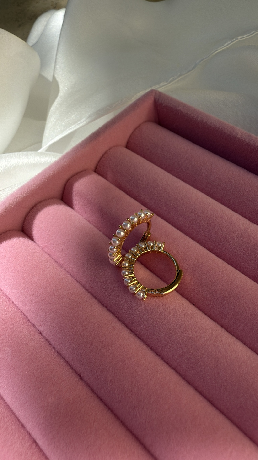 Brincos de argola dourados com pérolas numa caixa de veludo rosa