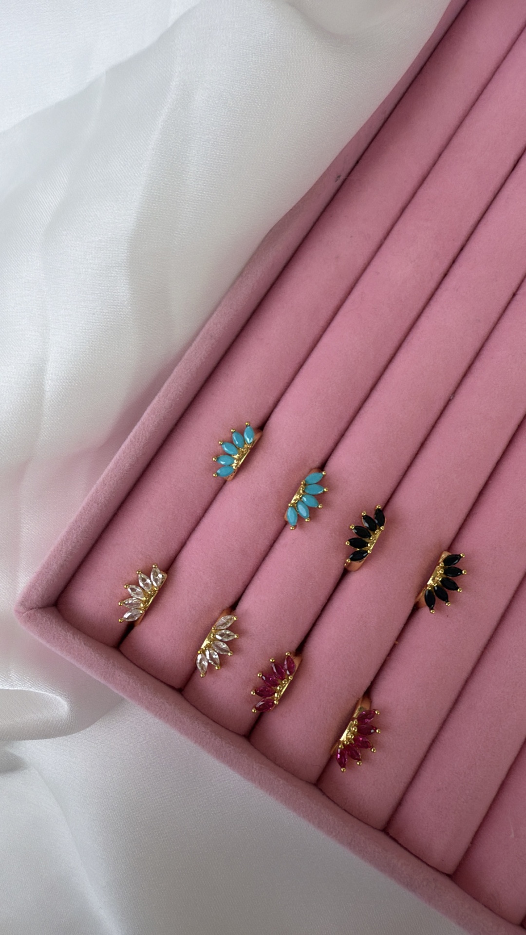 Brincos em ouro com pedras coloridas em suporte almofadado rosa