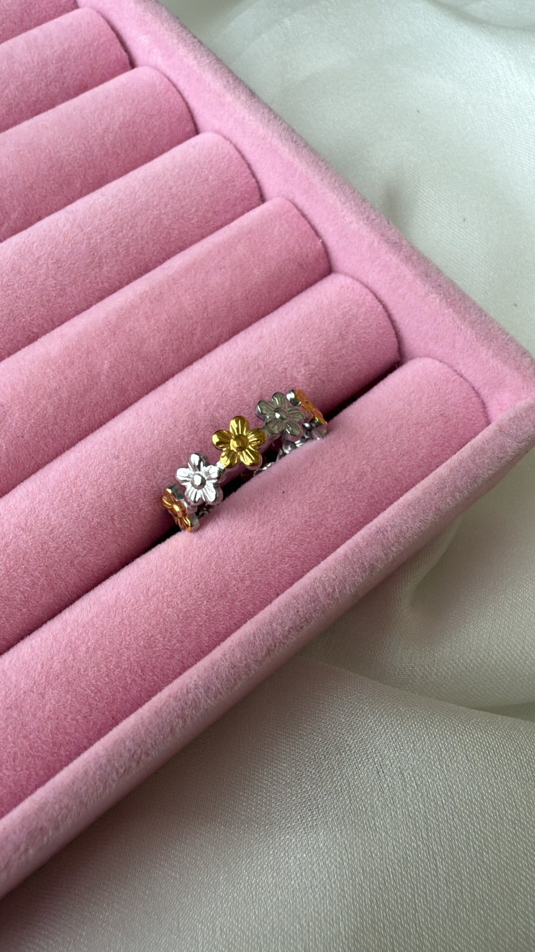anel metálico com flores prateado e dourado numa caixa de veludo rosa