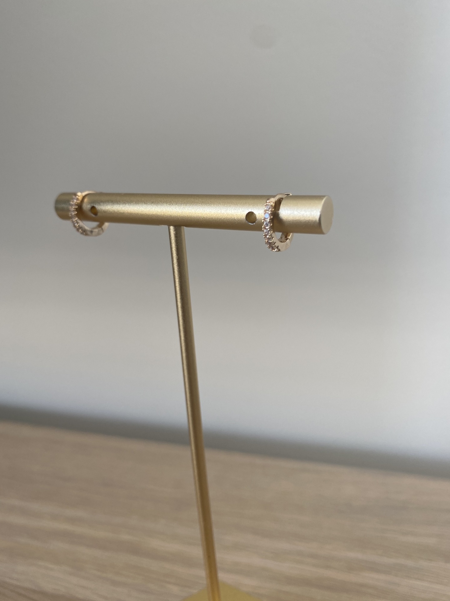 Brincos dourados com pedrinhas em suporte metálico