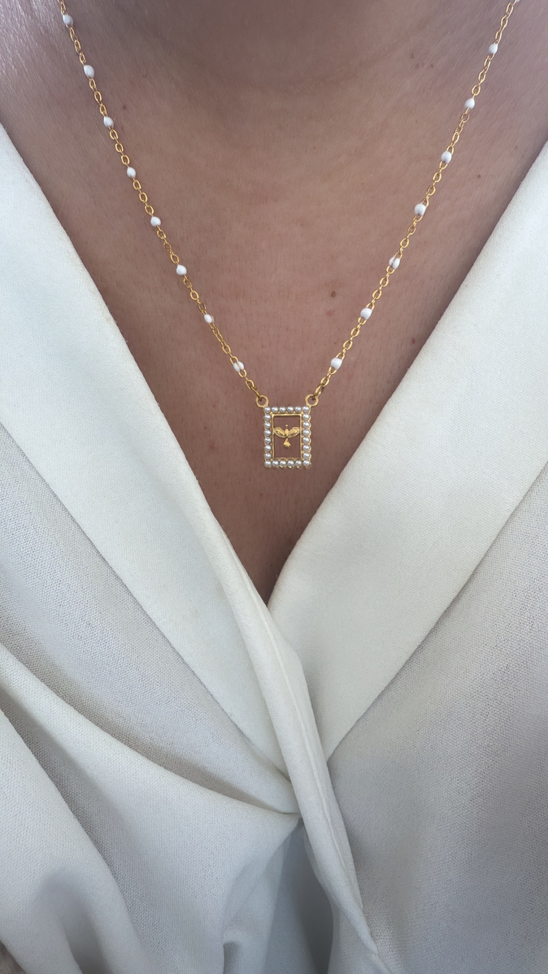 Colar dourado com pérolas e pendente retangular com figura dourada no centro