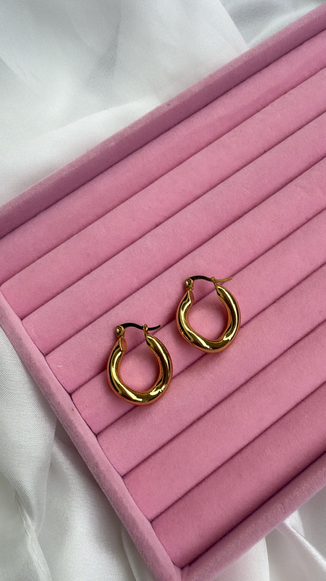brincos de argola dourada sobre estojo rosa veludo