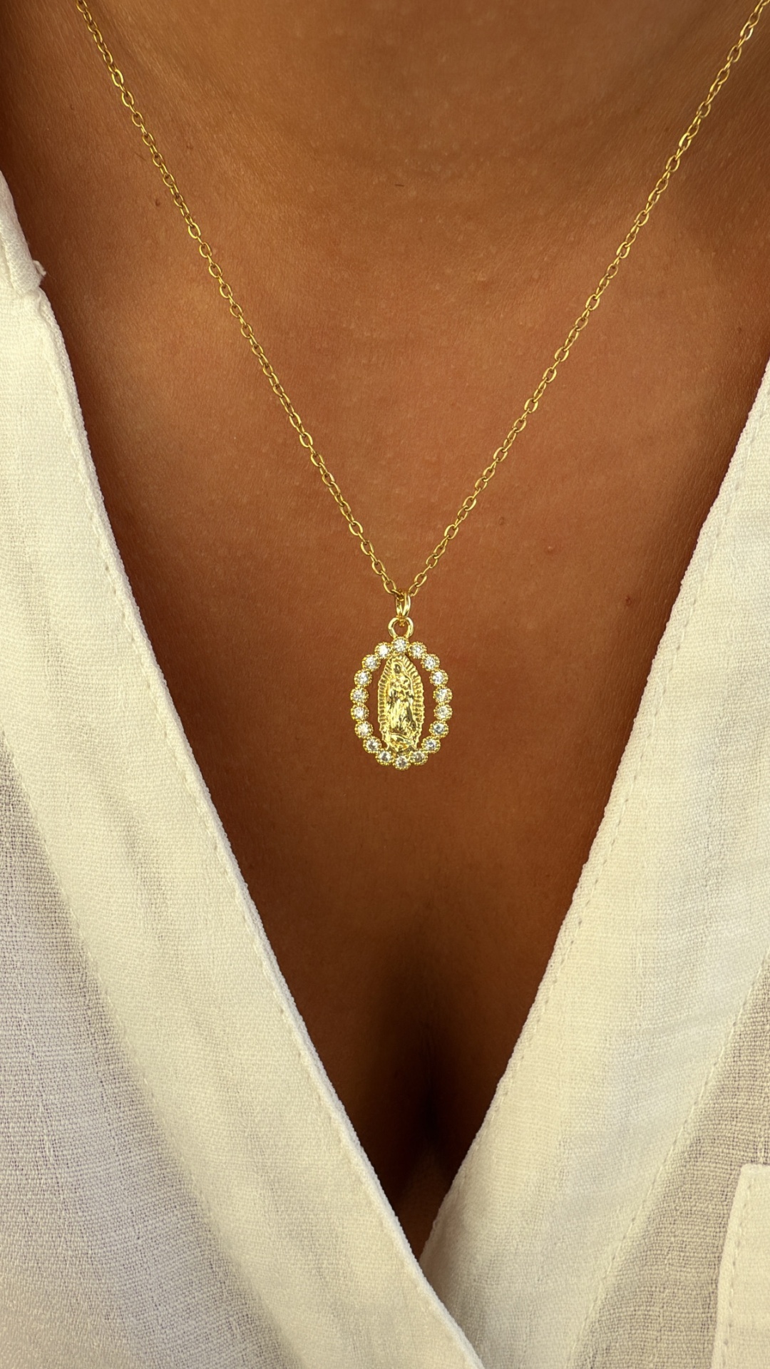Colar dourado com pendente oval e pérolas em vestido branco